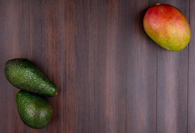 Draufsicht der grünen und frischen Avocado und der Mango auf einer hölzernen Oberfläche