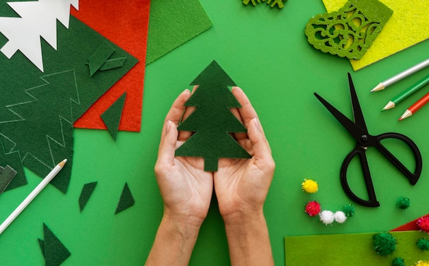 Draufsicht der Hände, die Weihnachtsbaum aus Papier halten