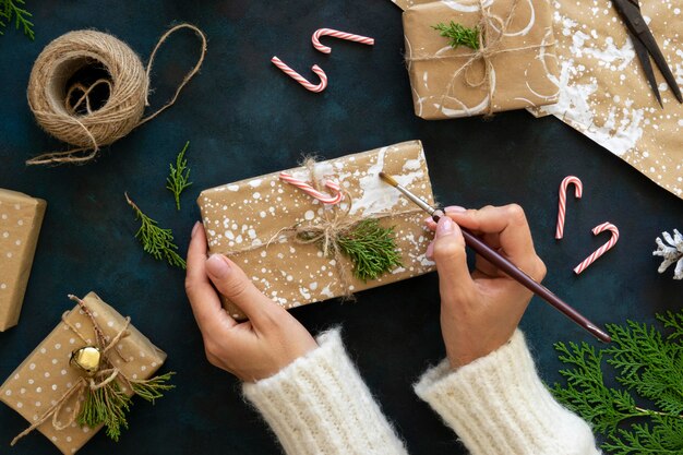 Draufsicht der Hände, die Weihnachtsgeschenk mit Farbe verzieren