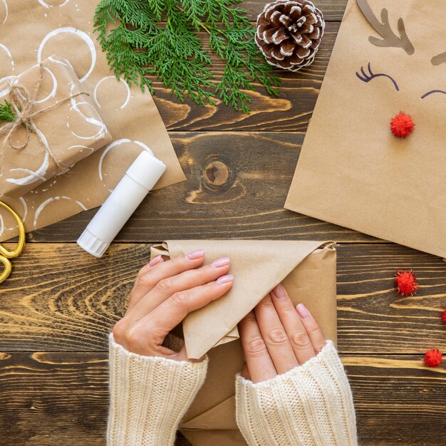 Draufsicht der Hände, die Weihnachtsgeschenkpapier einwickeln