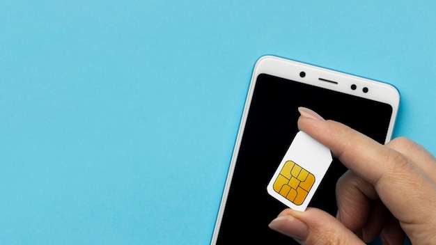 Draufsicht der Hand, die SIM-Karte mit Smartphone und Kopierraum hält