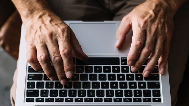 Draufsicht der Hand eines Mannes, die auf Tastatur schreibt