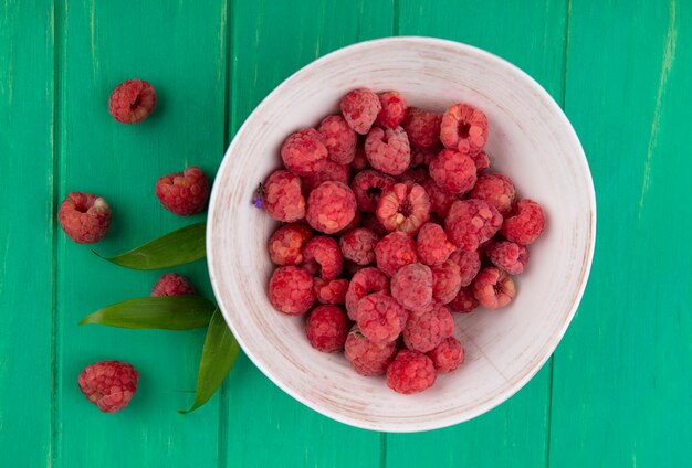 Kostenloses Foto draufsicht der himbeeren in der schüssel und auf der grünen oberfläche