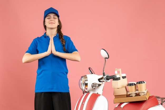 Draufsicht der hoffnungsvollen Kurierdame, die neben dem Motorrad mit Kaffee und kleinen Kuchen steht und von etwas auf pastellfarbenem Hintergrund träumt