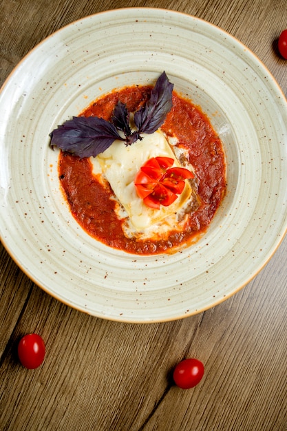 Kostenloses Foto draufsicht der italienischen lasagneplatte in der mit dunklem basilikum garnierten tomatensauce