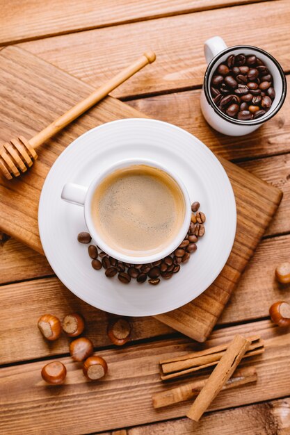 Draufsicht der Kaffeetasse verziert mit Kaffeebohnen, die auf hölzernem Servierbrett platziert werden