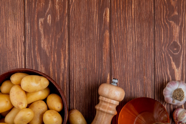 Draufsicht der Kartoffeln in der Schüssel mit Knoblauchsalz und Butter auf Holzoberfläche mit Kopienraum