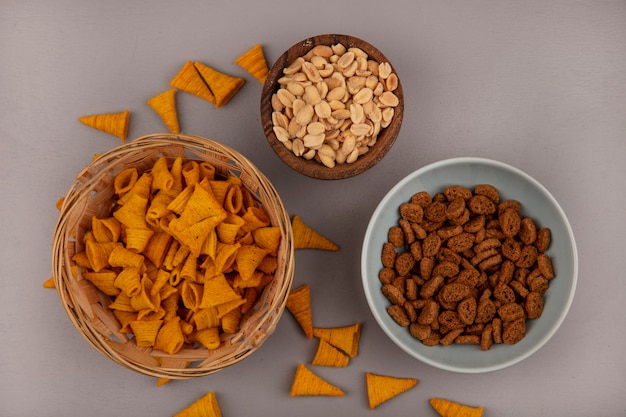 Draufsicht der knusprigen kegelförmigen gebratenen Maissnacks auf einem Eimer mit Pinienkernen auf einer Holzschale mit Roggen Zwieback auf einer Schüssel