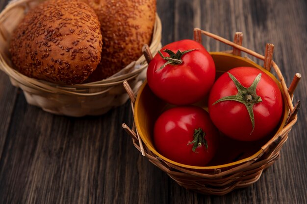Draufsicht der köstlichen Sesamfrikadellen auf einem Eimer mit frischen Tomaten auf einem Eimer auf einem hölzernen Hintergrund