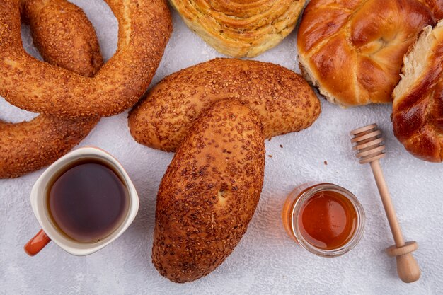 Draufsicht der köstlichen Sesamfrikadellen mit einer Tasse Tee und Honig auf einem Glas und verschiedenen Brötchen lokalisiert auf einem weißen Hintergrund