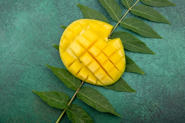 Draufsicht der köstlichen und frisch geschnittenen Mango mit Blatt auf Grün
