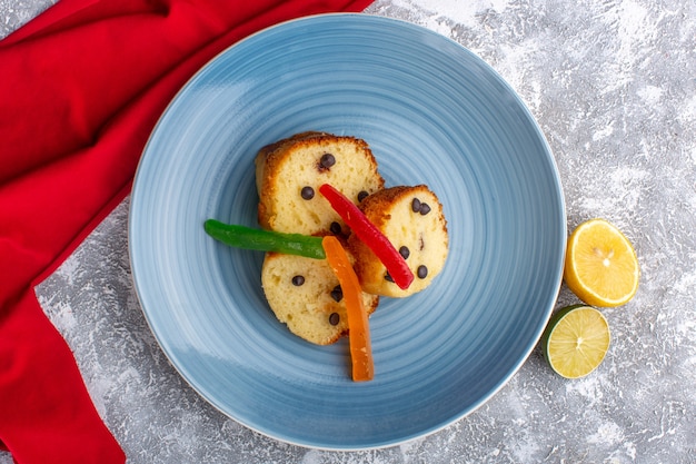 Draufsicht der Kuchenscheiben innerhalb der blauen Platte mit Schoko-Chips und Marmelade auf rustikaler grauer Oberfläche