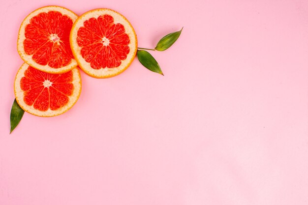 Draufsicht der leckeren Grapefruits auf rosa Oberfläche