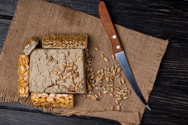 Draufsicht der leckeren Halva mit Honigriegeln mit Erdnüssen und Sonnenblumenkernen auf Sackleinen