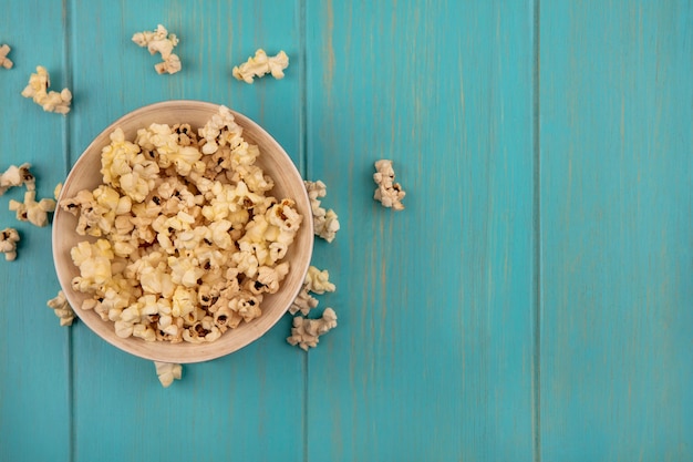 Draufsicht der leckeren Popcorns auf einer Schüssel auf einem blauen Holztisch mit Kopienraum