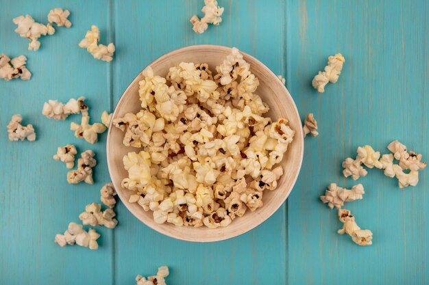 Draufsicht der leckeren Popcorns auf einer Schüssel auf einem blauen Holztisch