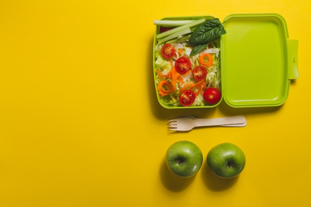 Draufsicht der Lunch-Box mit Salat und zwei Äpfel