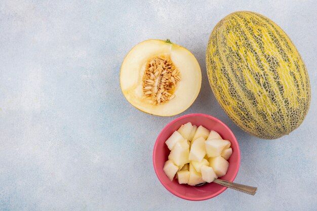 Draufsicht der Melone Melone mit Scheiben auf rosa Schüssel auf Weiß