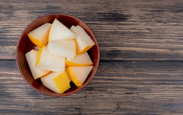 Draufsicht der Melonenscheiben in der Schüssel auf hölzernem Hintergrund mit Kopienraum