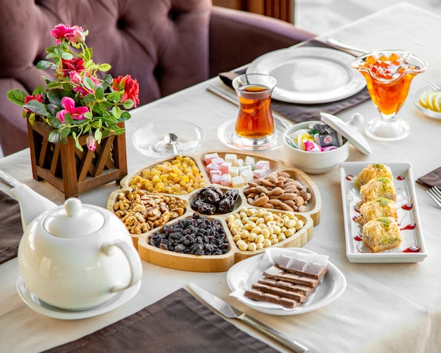 Draufsicht der Mischung von Nüssen mit getrockneten Früchten auf einem Holzteller serviert mit Tee und Süßigkeiten auf dem Tisch im Restaurant