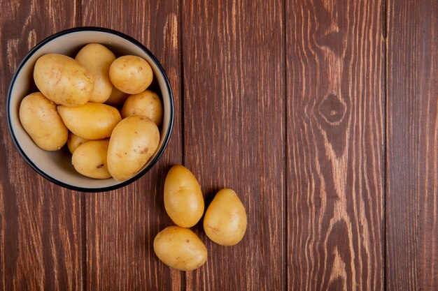 Draufsicht der neuen Kartoffeln in der Schüssel auf Holz mit Kopienraum