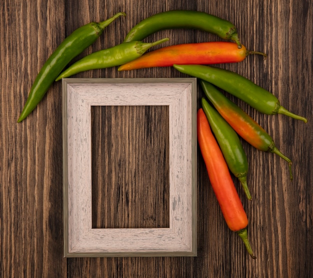 Kostenloses Foto draufsicht der orange und grünen chilischoten lokalisiert auf einer holzwand mit kopienraum