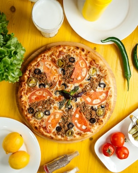 Draufsicht der pizza mit hackfleisch-tomaten und oliven auf einem holzteller