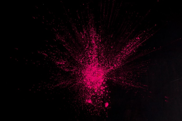 Draufsicht der rosa Farbe, die auf schwarzer Oberfläche explodiert