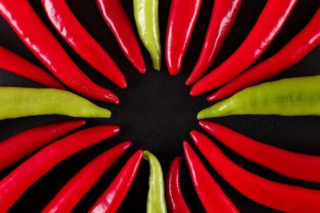 Kostenloses Foto draufsicht der roten und grünen paprikapfeffer über schwarze oberfläche