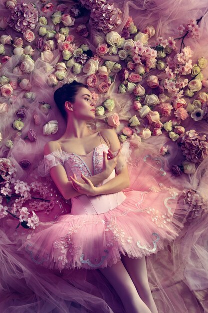 Draufsicht der schönen jungen Frau im rosa Ballett-Tutu, umgeben von Blumen