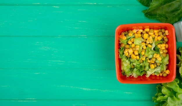 Draufsicht der Schüssel der gelben Erbse mit geschnittenem Salat und ganzem Spinat-Salat auf der rechten Seite und grüner Oberfläche mit Kopierraum