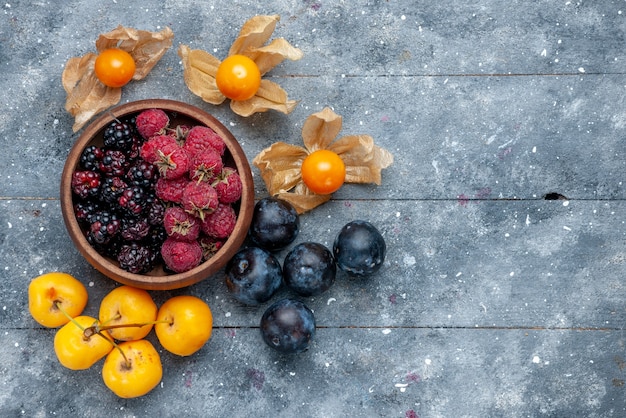 Draufsicht der Schüssel mit den frischen reifen Früchten der Beeren auf dem frischen milden Wald der grauen Beerenfrucht