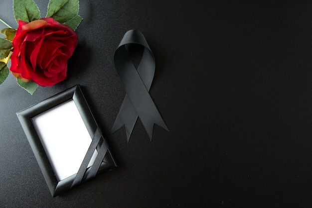Draufsicht der schwarzen Schleife mit roter Blume an dunkler Wand