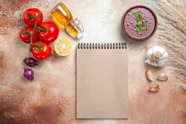 Draufsicht der Soße Soße Tomaten Zwiebel Zitronenöl in Flasche Knoblauchcreme Notizbuch