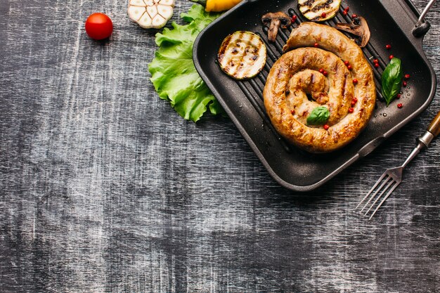 Draufsicht der Spirale grillte Wurst mit Gemüse in der Wanne