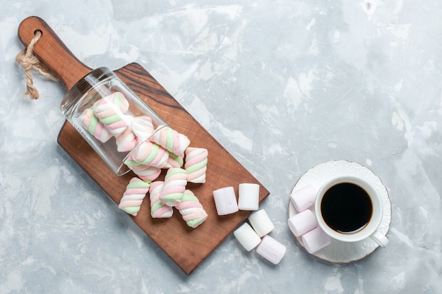 Kostenloses Foto draufsicht der süßen farbigen marshmallows mit tasse tee auf hellweißer oberfläche