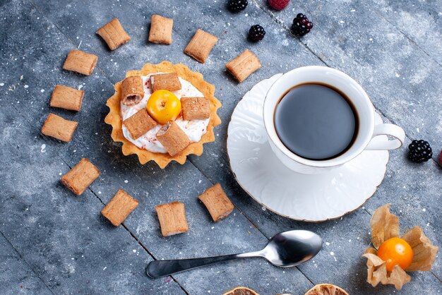 Draufsicht der Tasse Kaffee mit cremigem Kuchenkissen bildete Kekse zusammen mit Beeren auf grauer Beerenkeksplätzchenfotofarbe