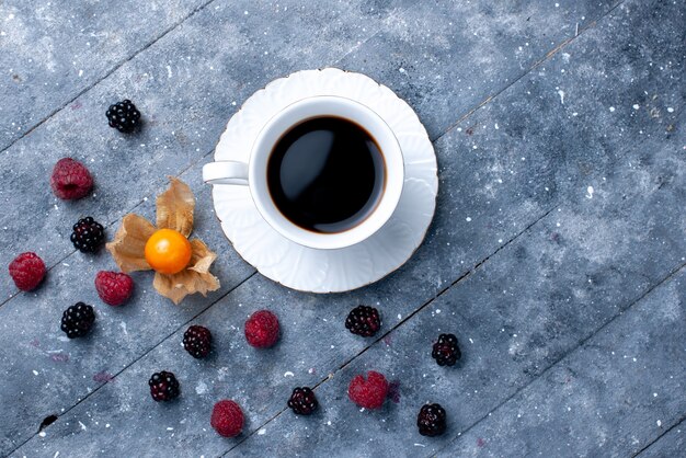 Draufsicht der Tasse Kaffee mit verschiedenen Beeren auf grauem Beerenfruchtkaffeegetränkfarbfoto