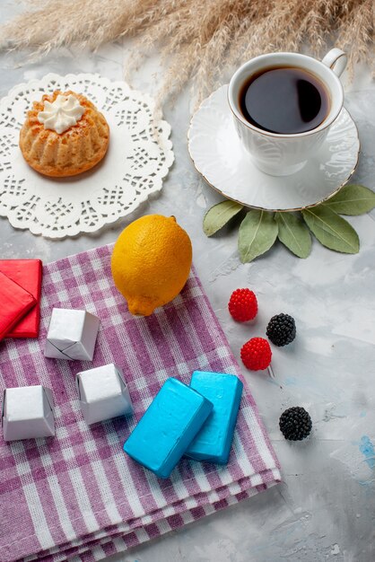 Draufsicht der Tasse Tee heiß innerhalb der weißen Tasse mit Kuchen Zitronenschokoladen auf hellem Schreibtisch, Tee Pralinenkuchen