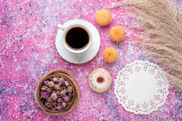 Draufsicht der Tasse Tee mit kleinen Kuchen auf der rosa Oberfläche