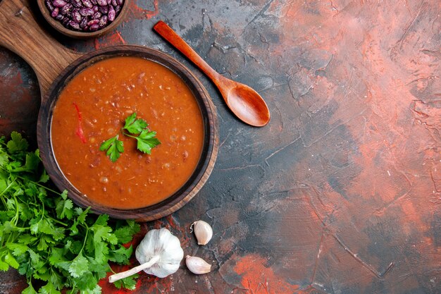 Draufsicht der Tomatensuppe auf einem braunen Schneidebrett auf einer gemischten Farbtabelle