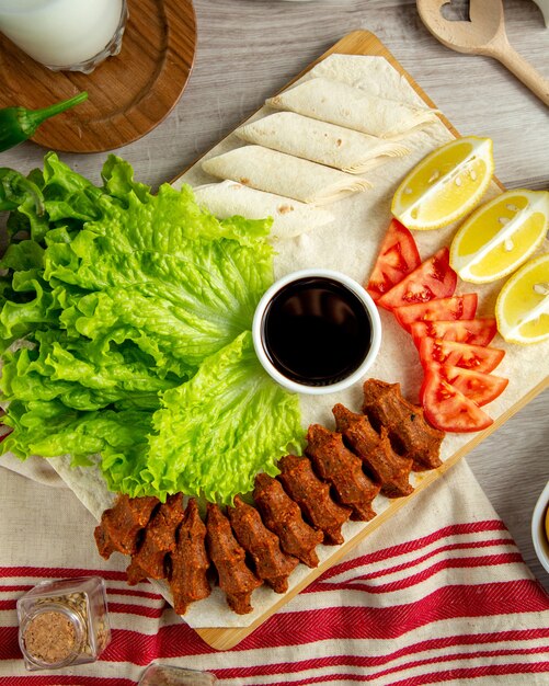 Draufsicht der türkischen Kofte-Fleischsalat-Tomaten-Zitrone