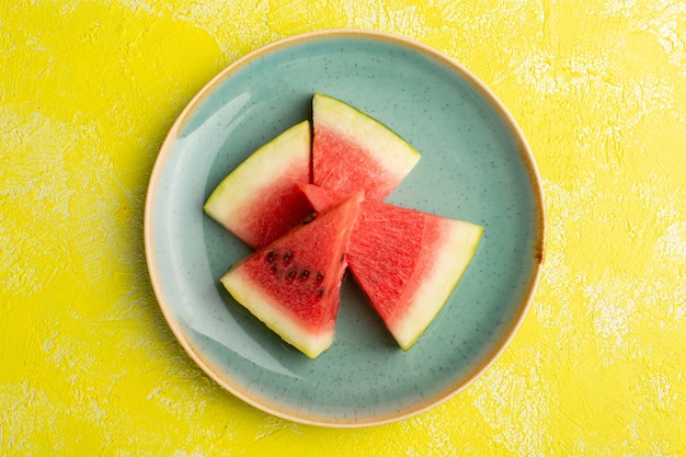 Draufsicht der Wassermelonenscheiben innerhalb der grünen Platte auf der gelben Oberfläche
