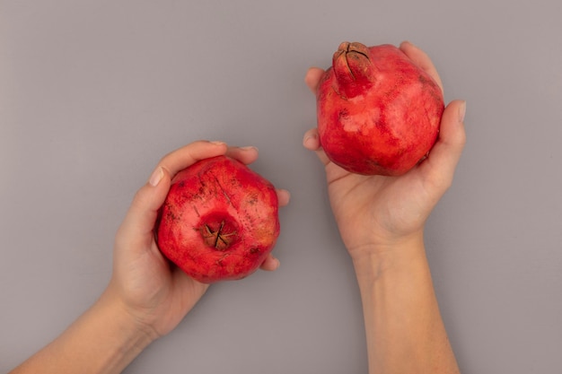 Draufsicht der weiblichen Hände, die frische rote Granatäpfel halten