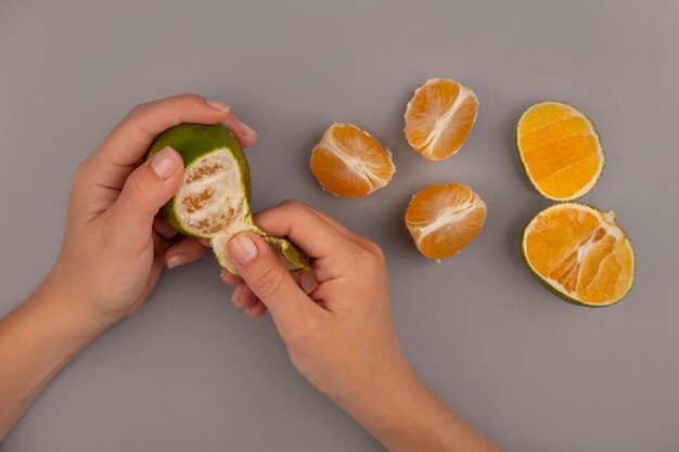Draufsicht der weiblichen Hand, die frische grüne Mandarine schält