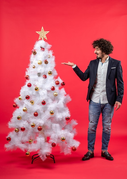 Draufsicht der Weihnachtsfeier mit bärtigem jungem Mann, der Weihnachtsbaum auf Rot zeigt