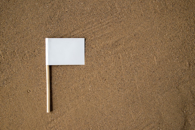 Draufsicht der weißen flagge auf braunem sand