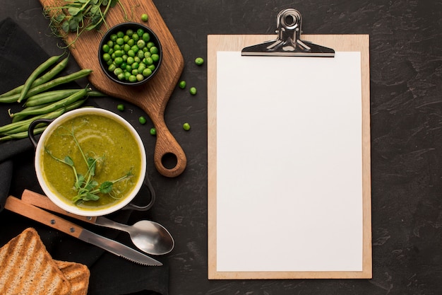 Kostenloses Foto draufsicht der wintererbsensuppe in der schüssel mit notizblock