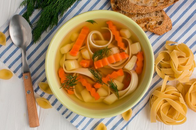 Draufsicht der Wintergemüsesuppe in der Schüssel mit Tagliatelle und Toast