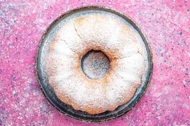 Draufsicht der Zuckerpulverkuchenrunde gebildet auf rosa Oberfläche